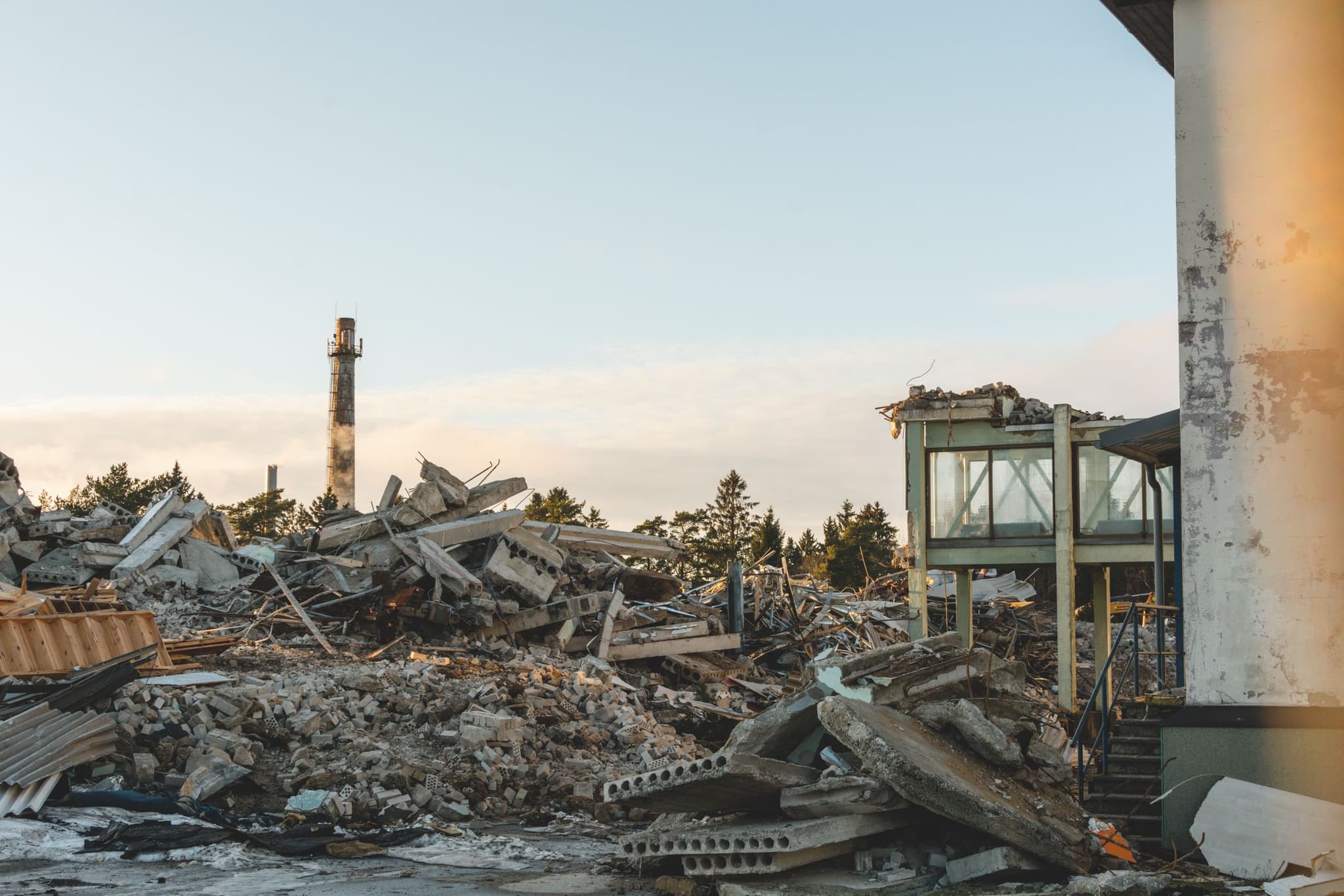 Nedrivningsplads i lavt eftermiddagslys med sorterede materialer i forgrunden